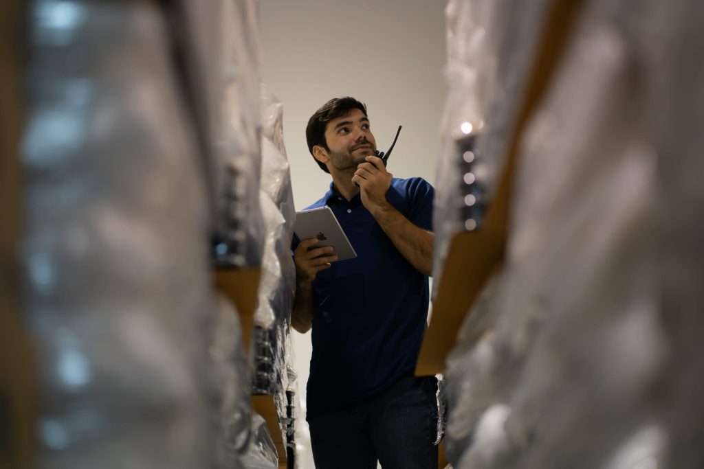 Distribution centre worker using a wireless while inspecting rows of material